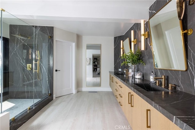 bathroom with hardwood / wood-style floors, vanity, walk in shower, and tasteful backsplash