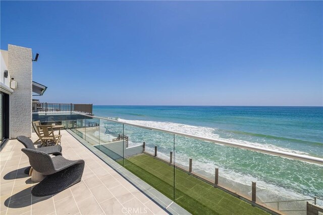 balcony featuring a view of the beach and a water view