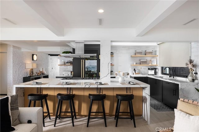 kitchen with beam ceiling, a large island, sink, a breakfast bar, and light wood-type flooring