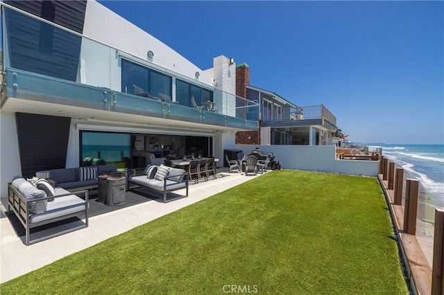 back of house featuring outdoor lounge area, a water view, a patio, and a lawn