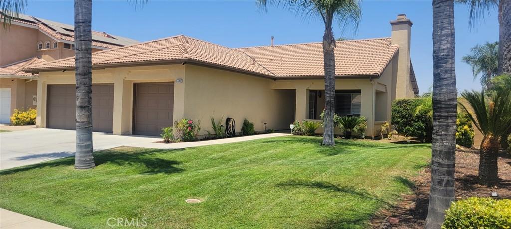 view of front facade with a tile roof, stucco siding, concrete driveway, an attached garage, and a front yard