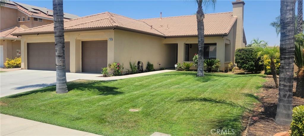 view of front of house featuring an attached garage, a tile roof, driveway, stucco siding, and a front lawn