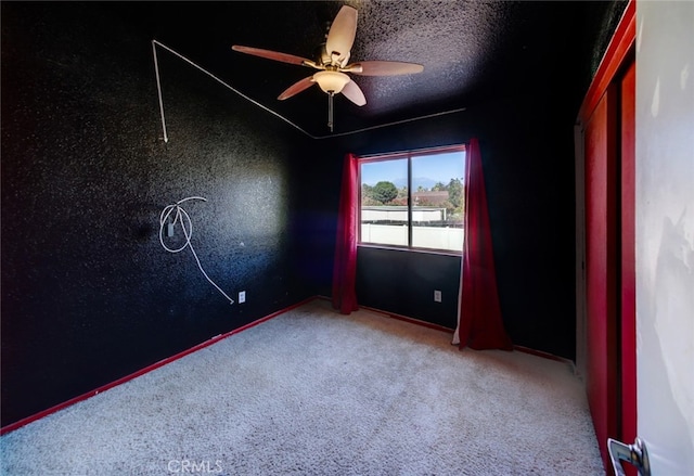 spare room with ceiling fan, a textured ceiling, and carpet