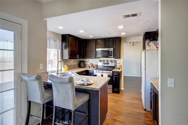 kitchen with stainless steel appliances, a wealth of natural light, a kitchen bar, and sink