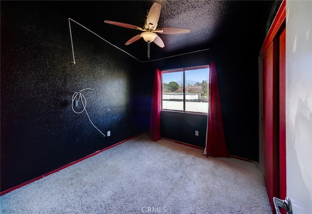 carpeted empty room with ceiling fan and a textured ceiling