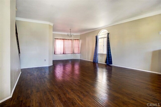 spare room featuring a notable chandelier, dark hardwood / wood-style floors, and ornamental molding