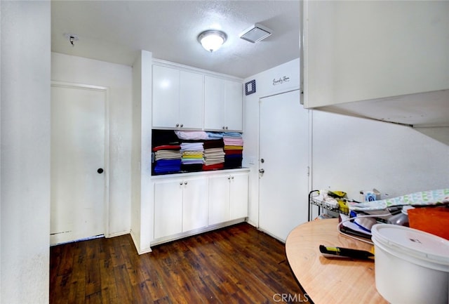 kitchen featuring a textured ceiling, dark wood-type flooring, and white cabinetry