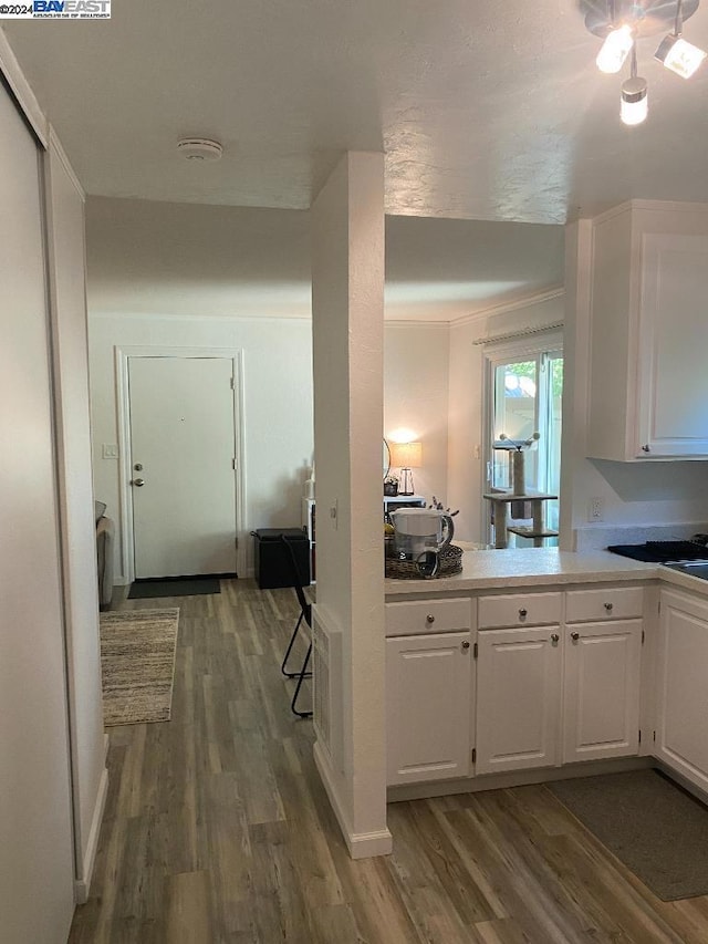 kitchen with hardwood / wood-style flooring, ornamental molding, and white cabinets