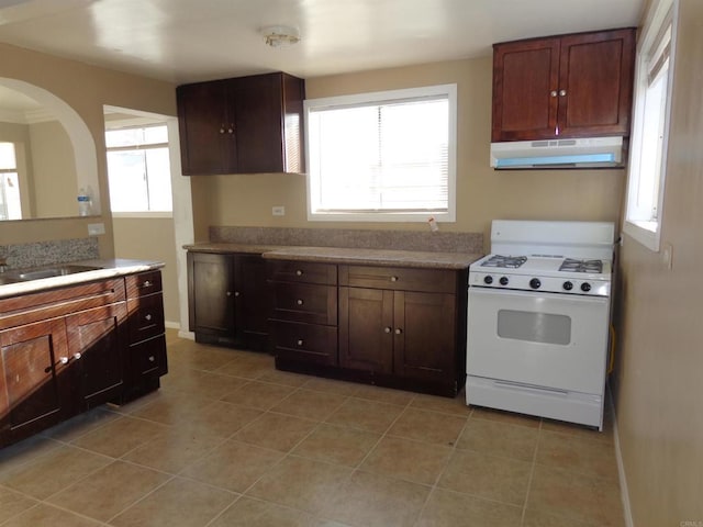 kitchen with white gas stove, light tile patterned flooring, extractor fan, and sink