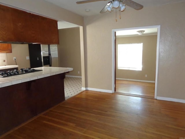 kitchen with hardwood / wood-style floors, black gas cooktop, tile counters, and ceiling fan