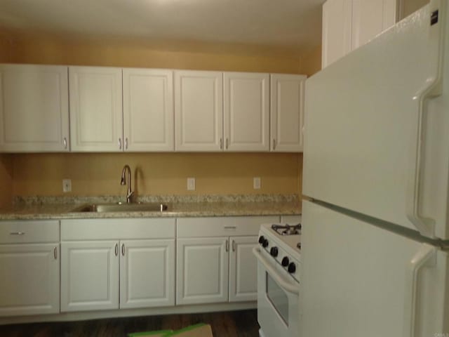 kitchen featuring white cabinets, white appliances, light stone counters, and sink