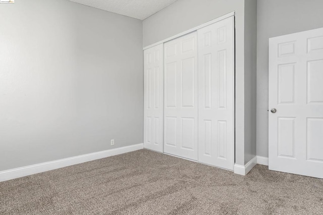 unfurnished bedroom featuring carpet flooring, a textured ceiling, and a closet