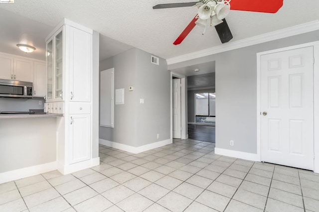 interior space featuring ceiling fan, light tile patterned floors, a textured ceiling, and ornamental molding