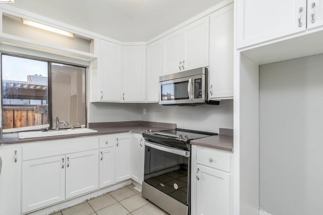 kitchen featuring light tile patterned flooring, sink, white cabinetry, and stainless steel appliances