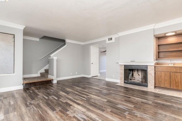 unfurnished living room with sink, built in features, ornamental molding, a fireplace, and dark hardwood / wood-style flooring