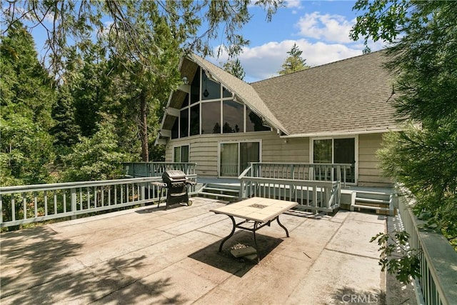 rear view of property with a patio, a wooden deck, and a sunroom