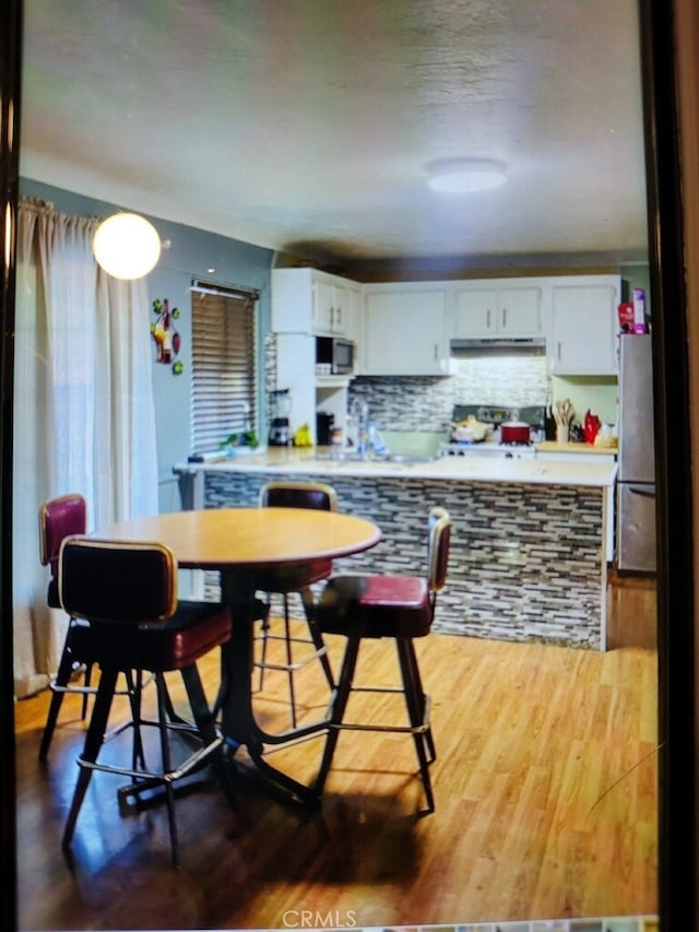 kitchen featuring white cabinets, hardwood / wood-style flooring, appliances with stainless steel finishes, and tasteful backsplash