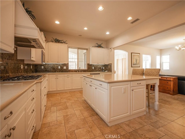 kitchen featuring white cabinetry, plenty of natural light, a kitchen island, and stainless steel gas cooktop