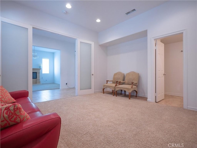 sitting room featuring a chandelier, french doors, and light colored carpet