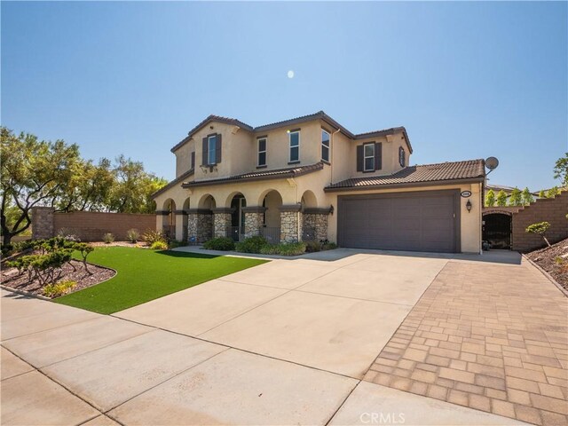 mediterranean / spanish house featuring a garage and a front yard