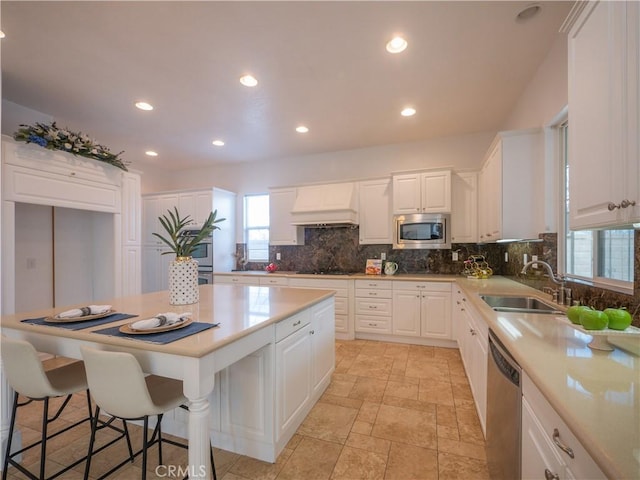 kitchen with appliances with stainless steel finishes, sink, white cabinets, and custom range hood