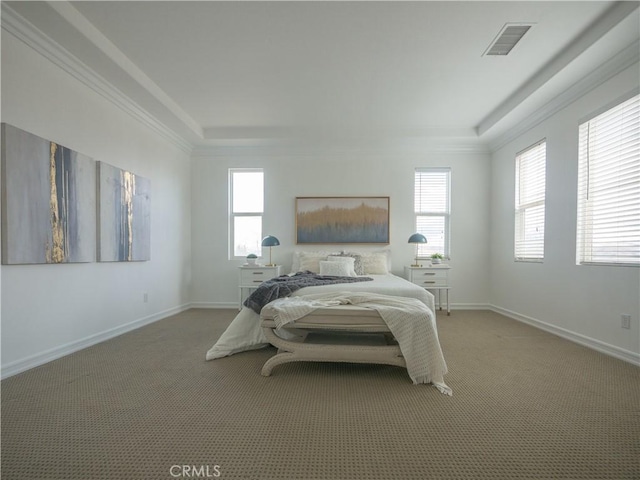 carpeted bedroom with crown molding, a raised ceiling, and multiple windows