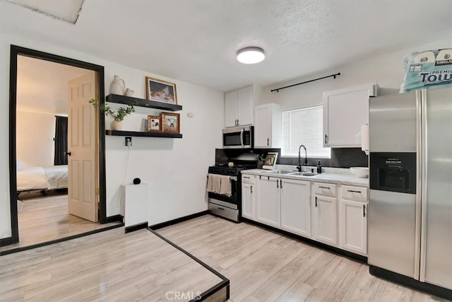 kitchen featuring sink, white cabinets, light hardwood / wood-style flooring, and stainless steel appliances