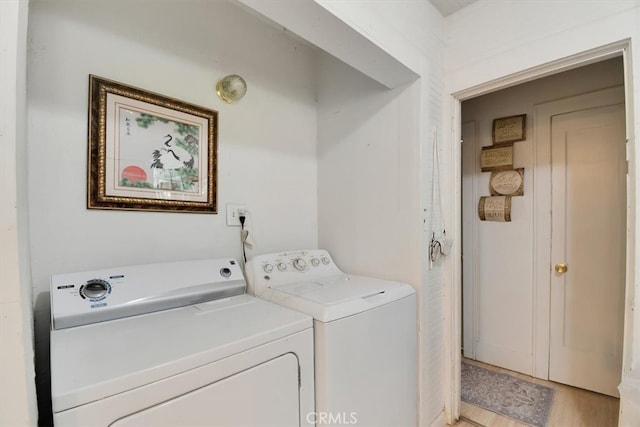 clothes washing area with washing machine and dryer and light hardwood / wood-style flooring