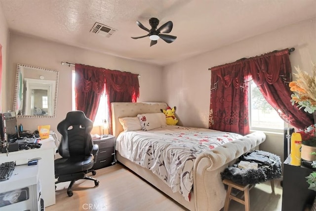 bedroom featuring a textured ceiling, light wood-type flooring, and ceiling fan