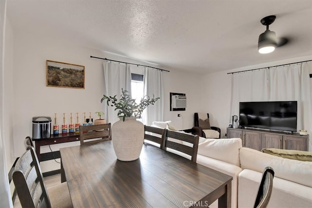 living room featuring hardwood / wood-style floors, a wall mounted AC, a textured ceiling, and ceiling fan