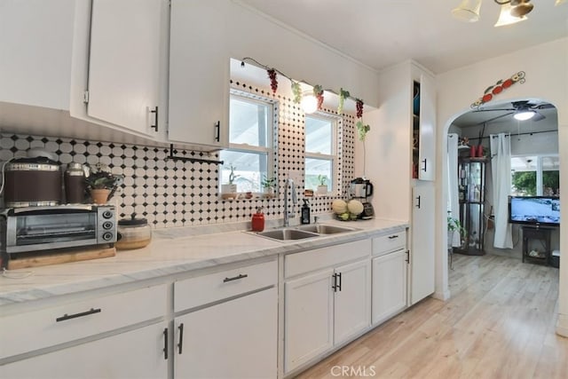 kitchen featuring sink, white cabinetry, light wood-type flooring, and a healthy amount of sunlight