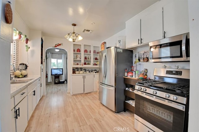 kitchen featuring pendant lighting, white cabinets, stainless steel appliances, and light wood-type flooring