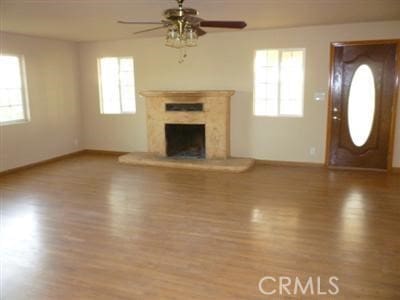 unfurnished living room with wood-type flooring, a fireplace, and ceiling fan