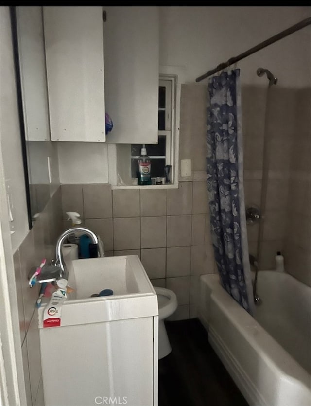 full bathroom featuring shower / bath combo with shower curtain, tile walls, vanity, and toilet