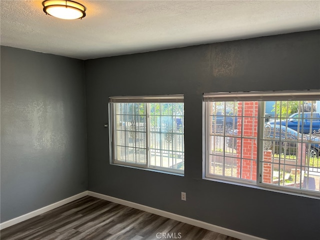 unfurnished room with a textured ceiling and dark hardwood / wood-style floors