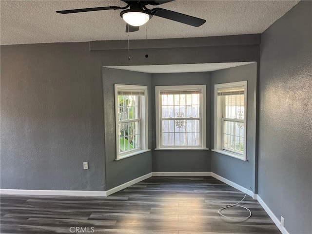 empty room with a textured ceiling, dark hardwood / wood-style floors, and ceiling fan