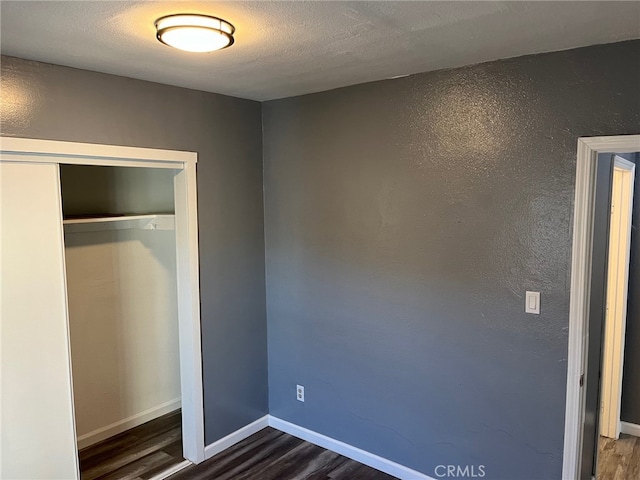 unfurnished bedroom with a closet and dark hardwood / wood-style flooring