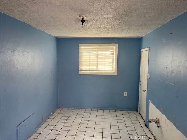 tiled empty room with a textured ceiling