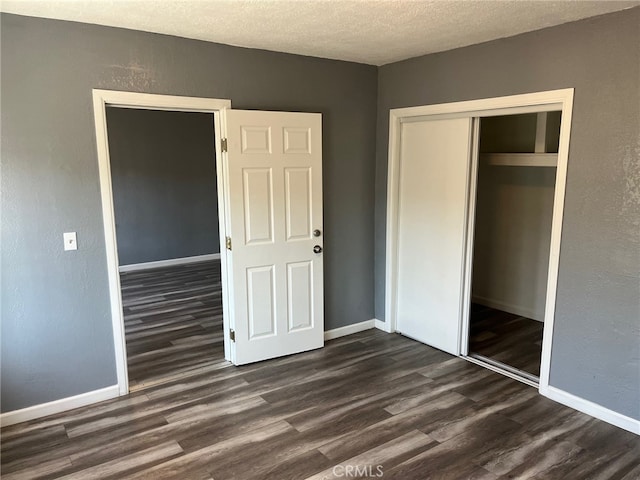 unfurnished bedroom with a textured ceiling, dark hardwood / wood-style floors, and a closet