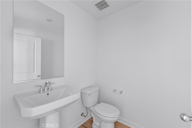 bathroom with wood-type flooring, toilet, and sink