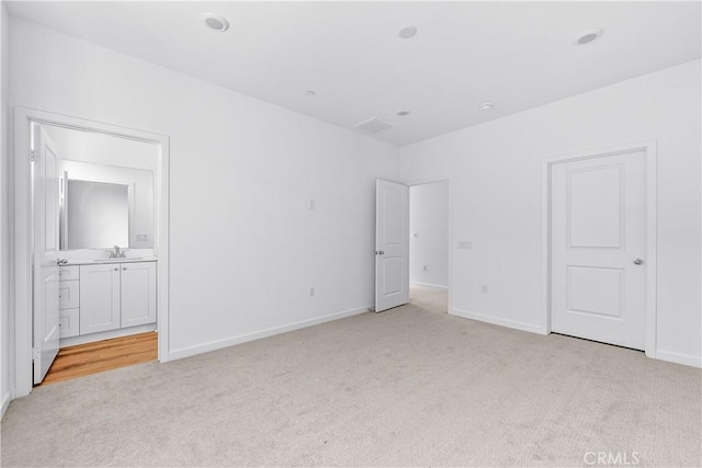 unfurnished bedroom with light colored carpet, connected bathroom, and sink