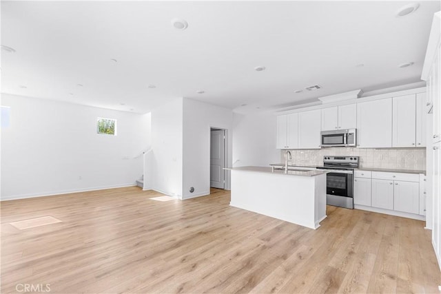 kitchen featuring white cabinetry, decorative backsplash, appliances with stainless steel finishes, and a center island with sink