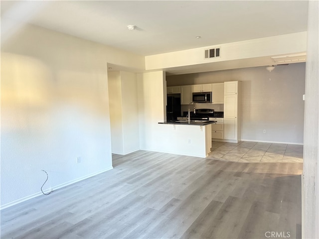 unfurnished living room with sink and light hardwood / wood-style floors