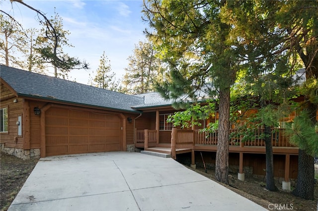 view of front of home with concrete driveway, a garage, and a shingled roof