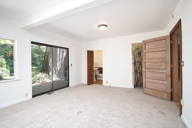 empty room with beamed ceiling and light colored carpet