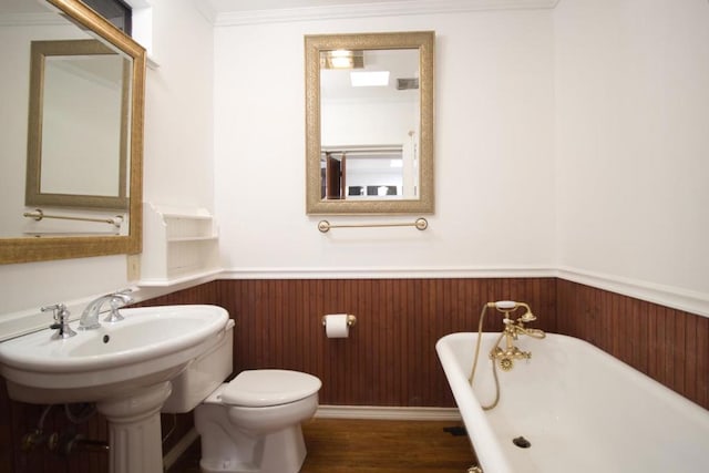 bathroom with hardwood / wood-style floors, a washtub, toilet, and ornamental molding