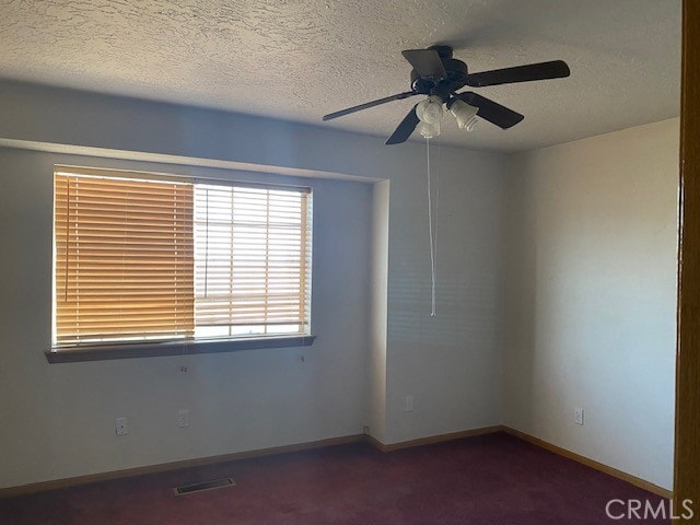 unfurnished room featuring dark colored carpet, ceiling fan, and a textured ceiling