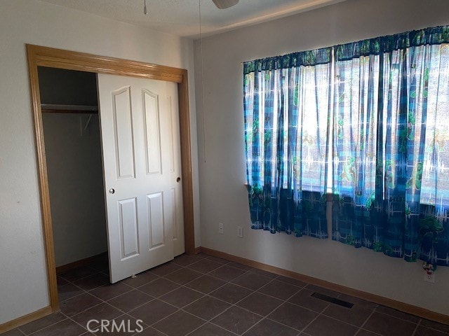 unfurnished bedroom with dark tile patterned floors and a closet