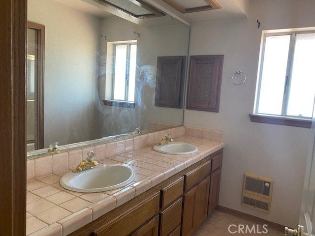 bathroom with vanity, tile patterned floors, heating unit, and a healthy amount of sunlight