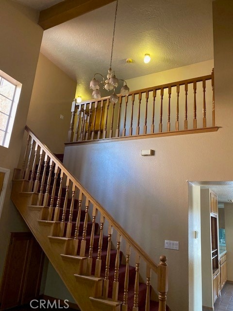 stairs with a textured ceiling, vaulted ceiling, and a chandelier